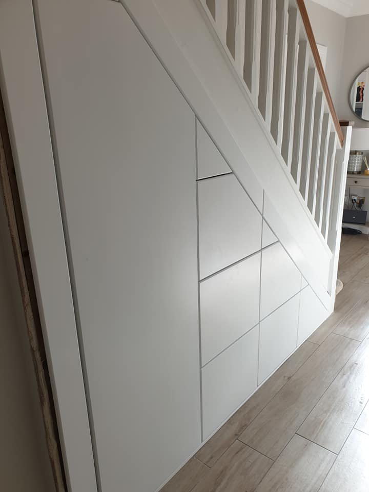 Flush white storage doors fitted under a staircase