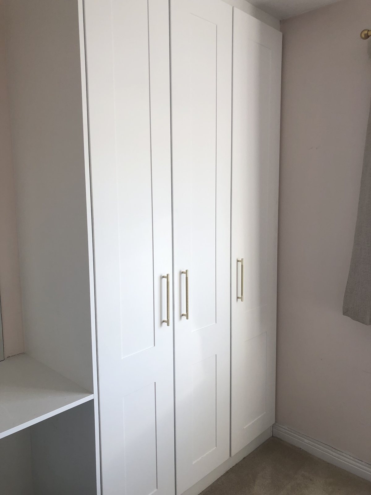 A tall fitted white wardrobe with long handles